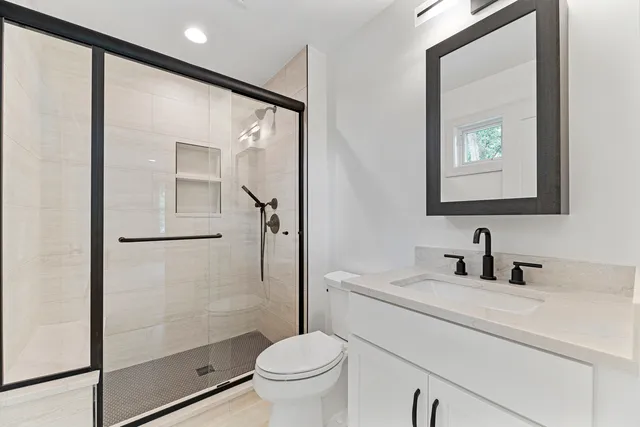a bathroom with a shower sink vanity mirror and toilet