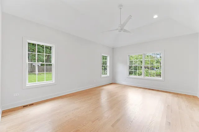 an empty room with wooden floor and windows