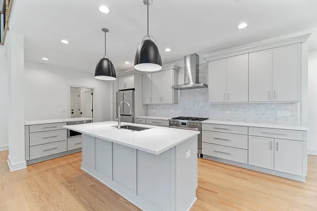 a kitchen with a stove a sink a window and wooden floor