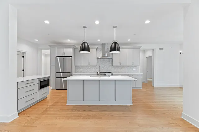 a large white kitchen with kitchen island a sink a stove and a refrigerator