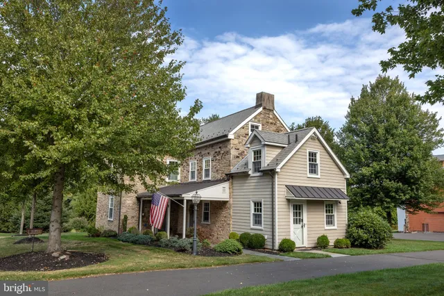 a view of a white house next to a yard with big trees