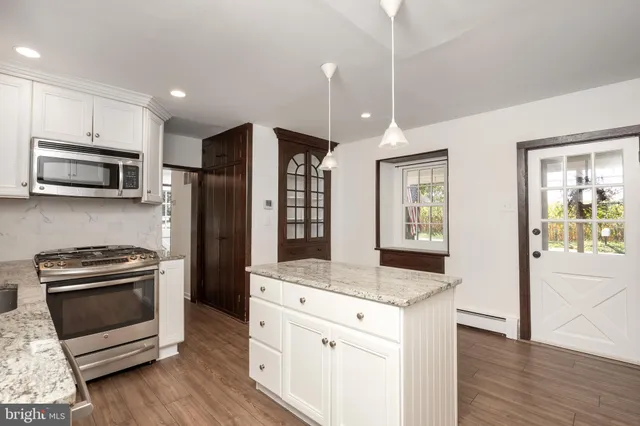a kitchen with stainless steel appliances kitchen island granite countertop a stove a sink and a refrigerator