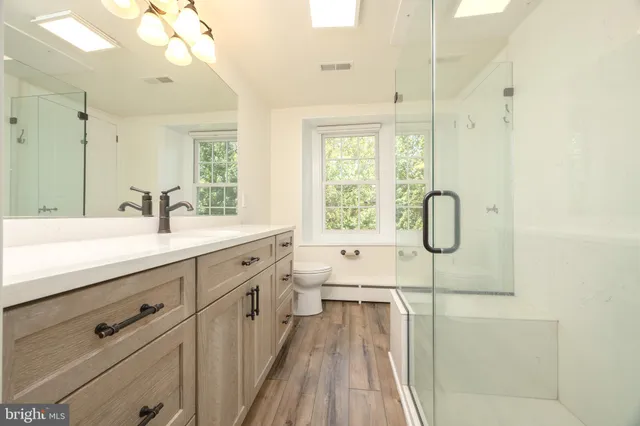 a spacious bathroom with a double vanity sink toilet mirror and shower