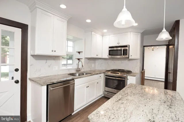 a kitchen with stainless steel appliances granite countertop a stove top oven a sink a microwave and a refrigerator