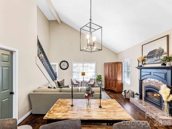 a living room with dining table a rug potted plant and a window