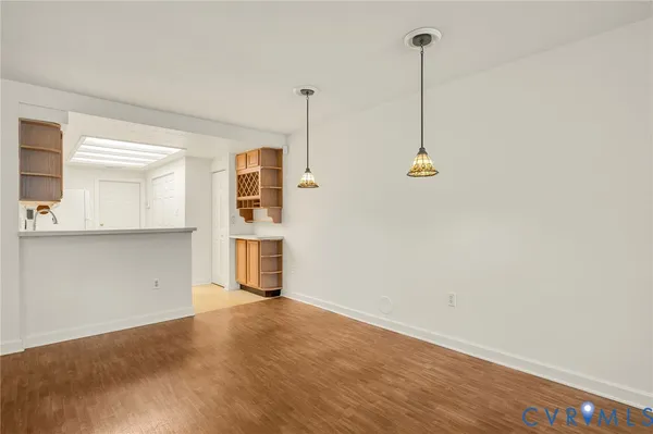 a view of empty room with wooden floor and kitchen