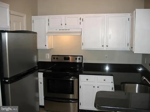 a kitchen with a refrigerator and white cabinets