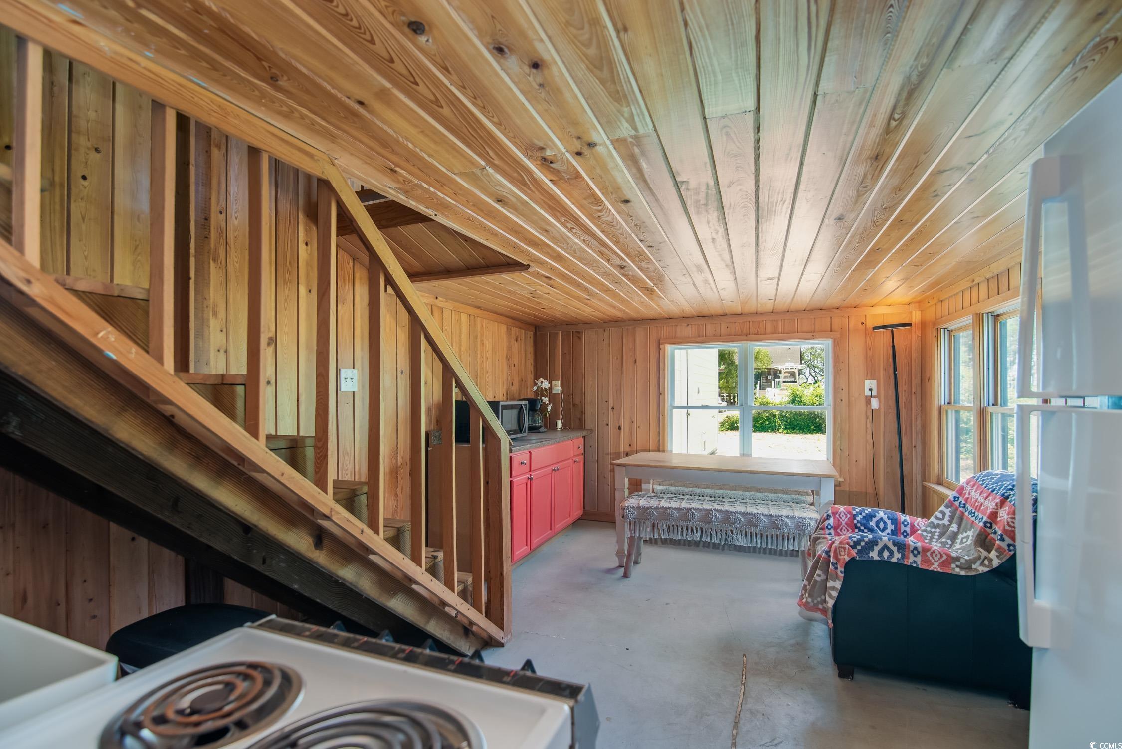 127 Brown Pelican Loop Pawleys Island, SC 29585 - Photo 7 of 31 Miscellaneous room with wood ceiling, concrete floors, wood walls, and stairway