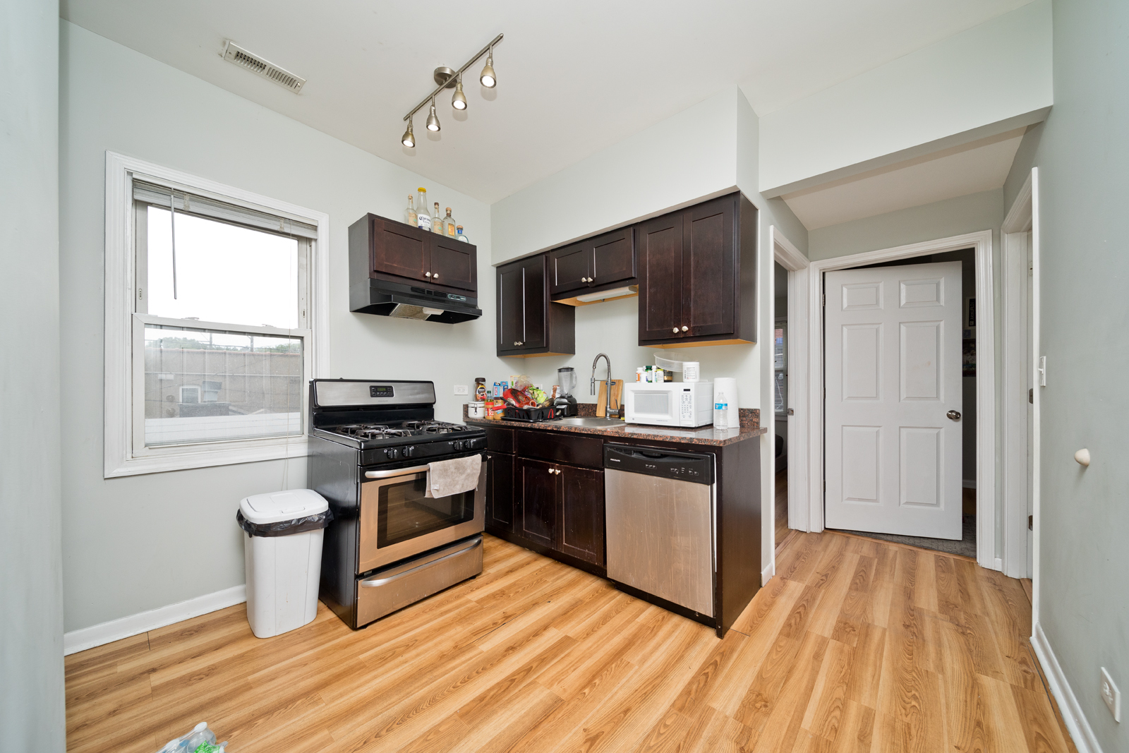 1431 West Flournoy Street, Unit 2R Chicago, IL 60607 - Photo 5 of 9 a kitchen with stainless steel appliances granite countertop a stove top oven a sink dishwasher and a microwave oven with wooden floor