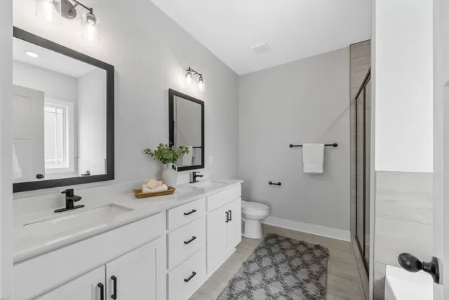 a bathroom with a double vanity sink toilet and shower