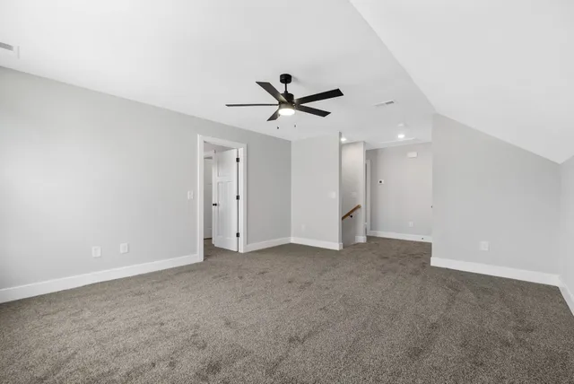 an empty room with chandelier fan and windows