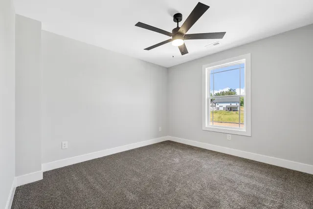 an empty room with windows and fan
