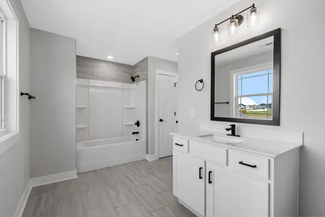 a bathroom with a sink a mirror a vanity and a bathtub