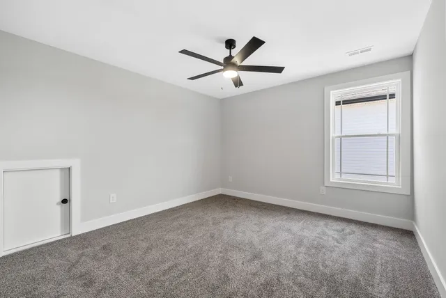 an empty room with a window and a fan
