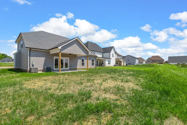 a view of a white house next to a yard with big trees