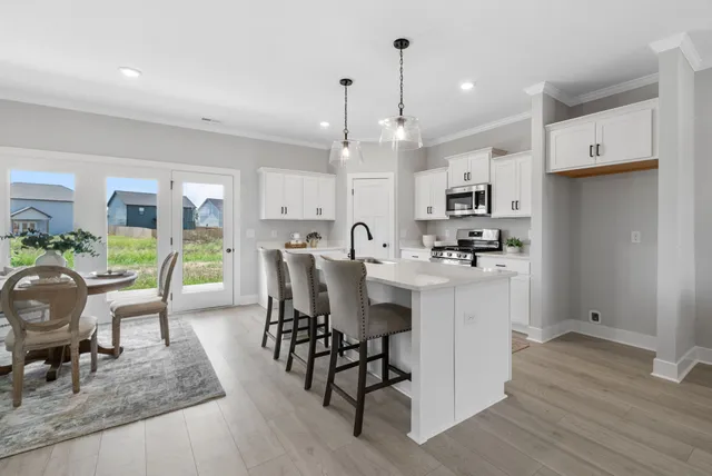 a kitchen with stainless steel appliances kitchen island granite countertop a table chairs and a refrigerator