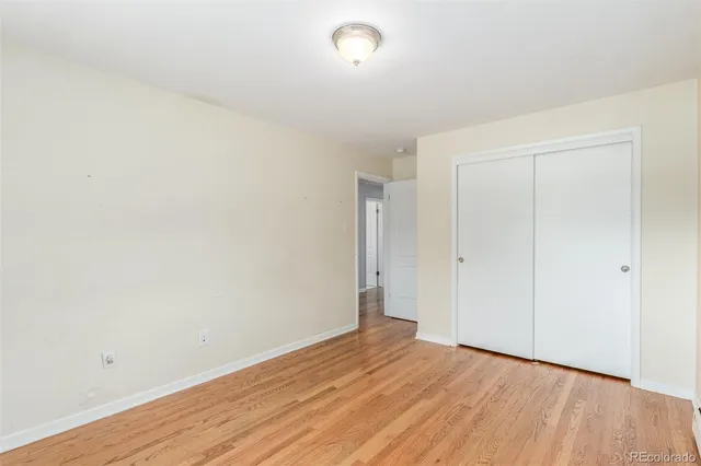 a view of an empty room with wooden floor and a fireplace