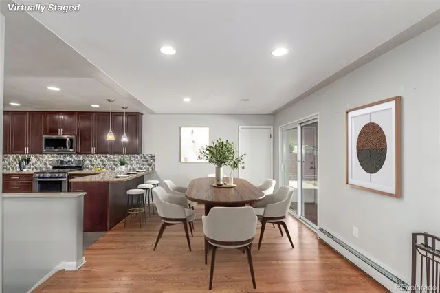 a kitchen with stainless steel appliances granite countertop wooden cabinets a sink a stove a dining table and chairs