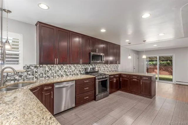 a kitchen with stainless steel appliances granite countertop a refrigerator a stove and a sink