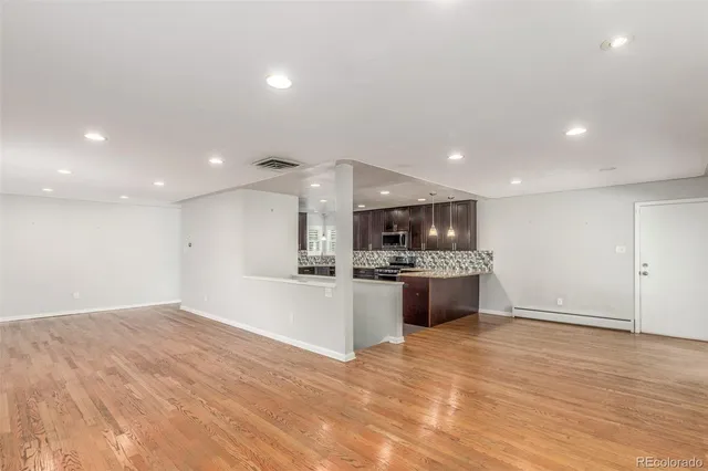 a view of an empty room with wooden floor and windows