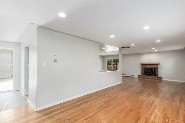 a view of an empty room with wooden floor and windows
