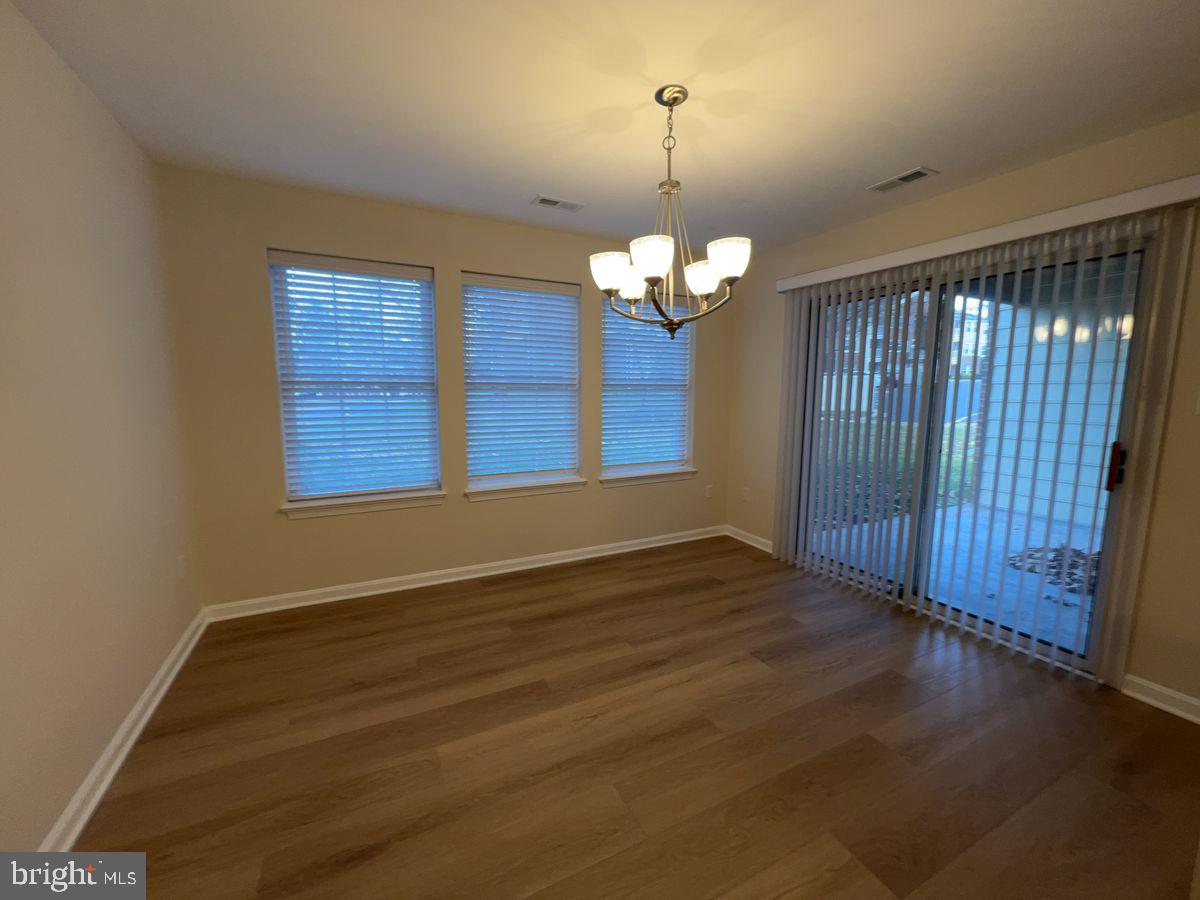 2400 Ellsworth Way, Unit 1C Frederick, MD 21702 - Photo 5 of 17 an empty room with wooden floor chandelier and windows