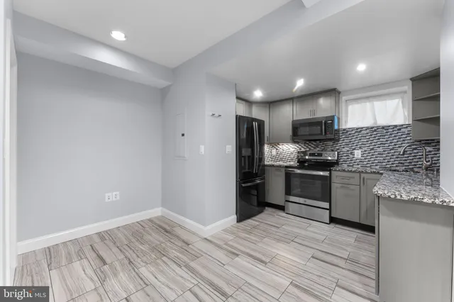 a kitchen with granite countertop a refrigerator stove top oven and sink