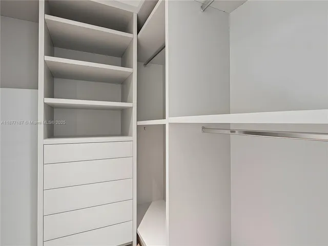 a spacious bedroom with a large bed a chandelier and windows