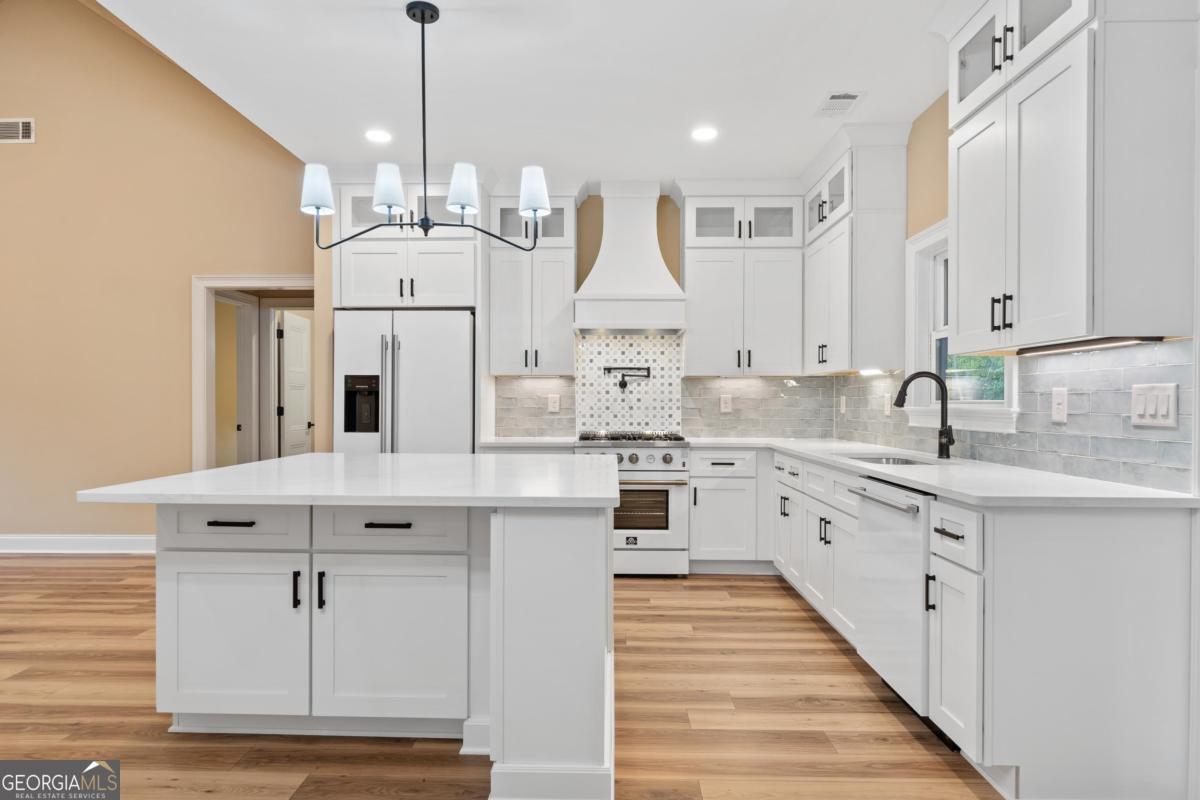 118 Southshore Road Eatonton, GA 31024 - Photo 4 of 42 a large white kitchen with granite countertop a sink white cabinets and white appliances