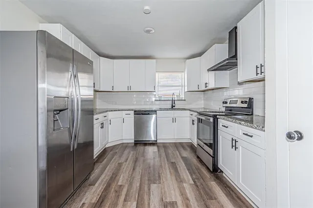 a kitchen with white cabinets stainless steel appliances and a window