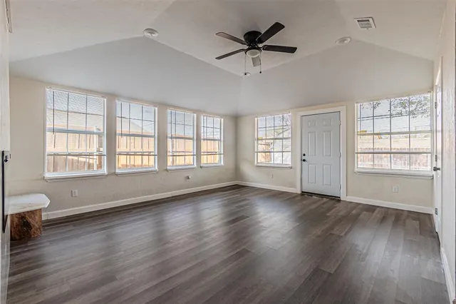 an empty room with wooden floor and windows