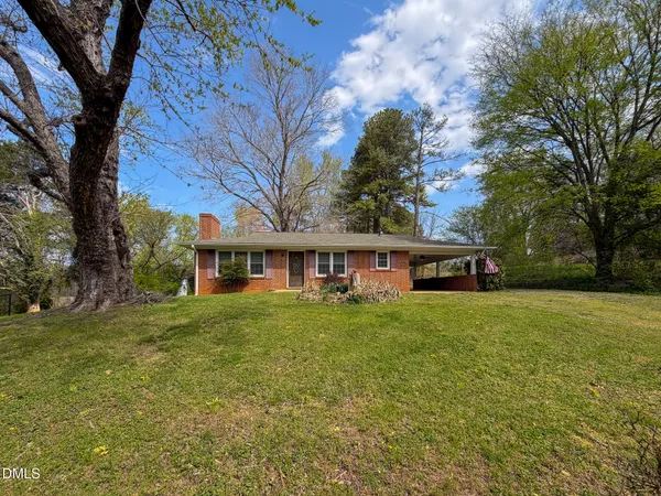 a view of a yard in front of a house with large trees