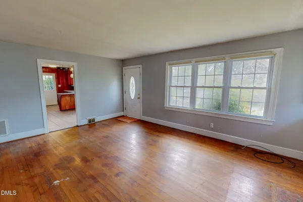 an empty room with wooden floor and windows
