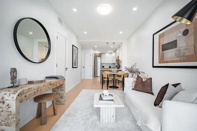 a living room with furniture a mirror and a potted plant