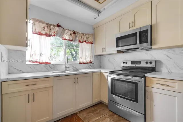 a kitchen with stainless steel appliances granite countertop white cabinets a sink and a window