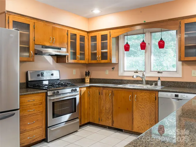 a kitchen with stainless steel appliances granite countertop a sink and a refrigerator