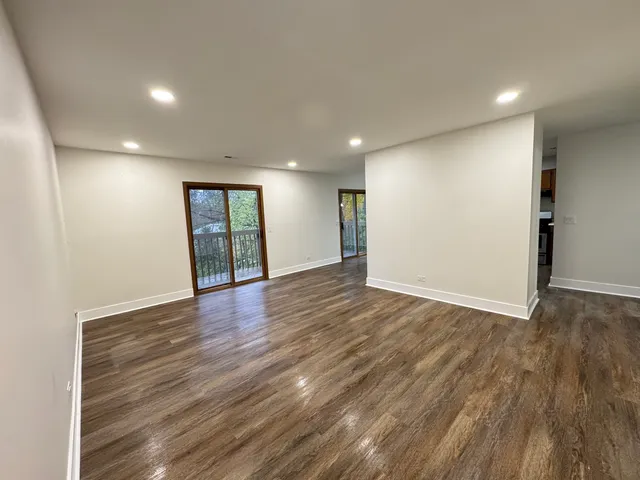 a view of an empty room with wooden floor and window