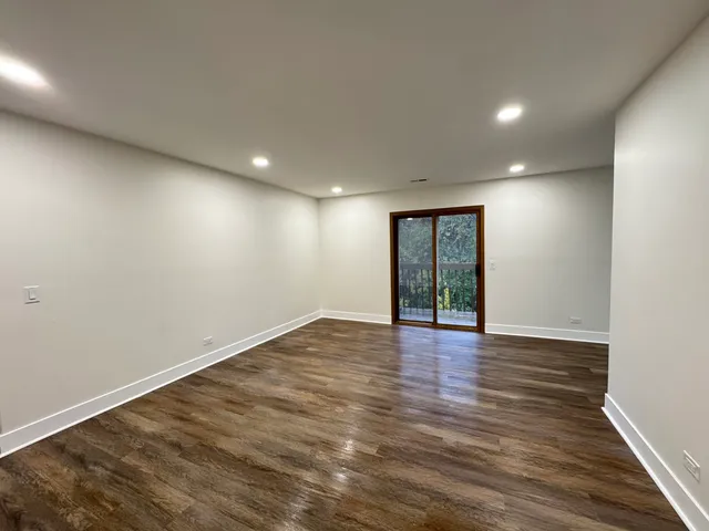 a view of an empty room with wooden floor and window