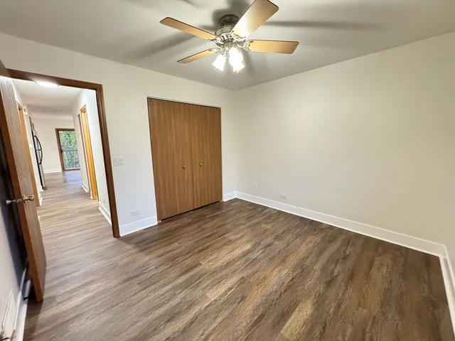 an empty room with wooden floor and a ceiling fan
