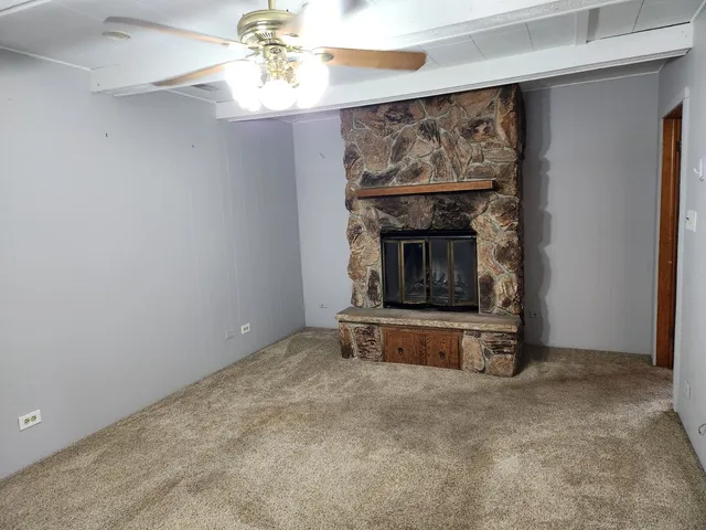 an empty room with a fireplace and chandelier fan