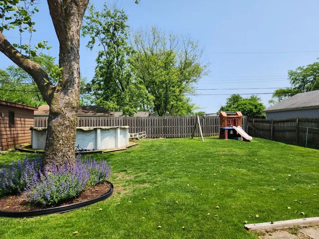 a view of a backyard with table and chairs potted plants and a large tree