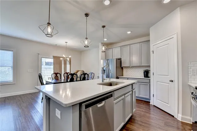 a kitchen with stainless steel appliances granite countertop a sink a refrigerator and wooden floor