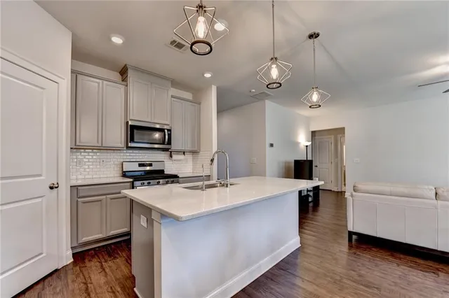 a large kitchen with stainless steel appliances a stove refrigerator and microwave