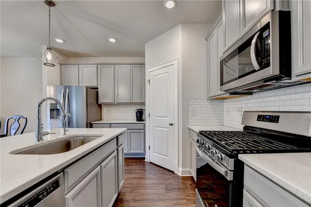 a kitchen with stainless steel appliances a sink a stove a microwave a sink a refrigerator and cabinets