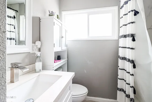 a bathroom with a sink a toilet and shower curtain