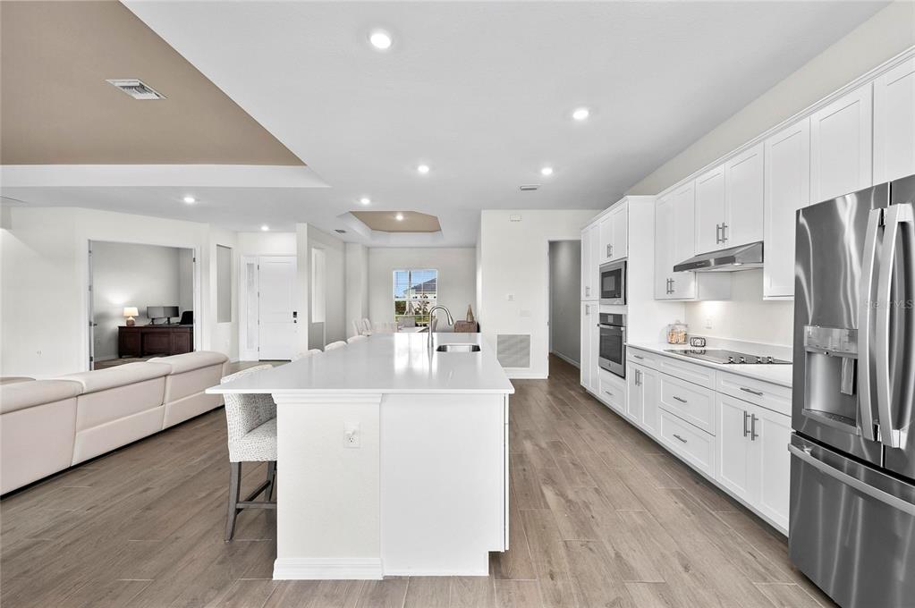 17341 Sandpearl Road Venice, FL 34293 - Photo 18 of 95 a large white kitchen with stainless steel appliances kitchen island a large counter top and a stove top oven