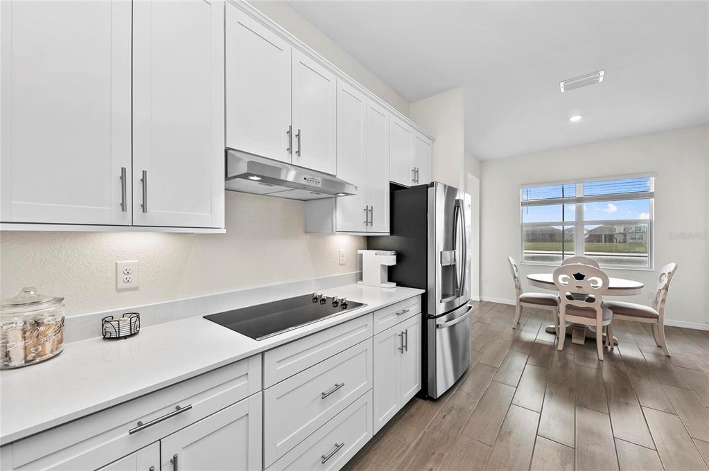 17341 Sandpearl Road Venice, FL 34293 - Photo 21 of 95 a kitchen with stainless steel appliances granite countertop a refrigerator stove and white cabinets with wooden floor