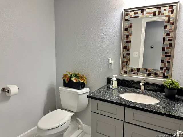 a bathroom with a granite countertop toilet sink and mirror