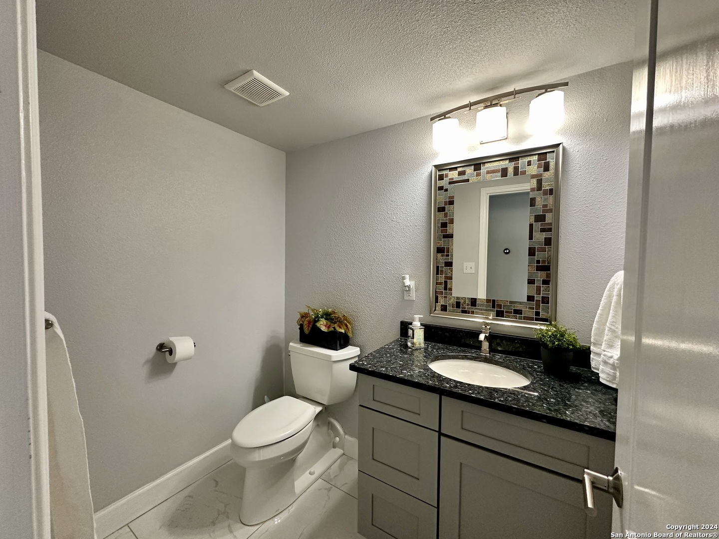 7701 Wurzbach Road, Unit 2301 San Antonio, TX 78229 - Photo 7 of 36 a bathroom with a granite countertop sink toilet and mirror