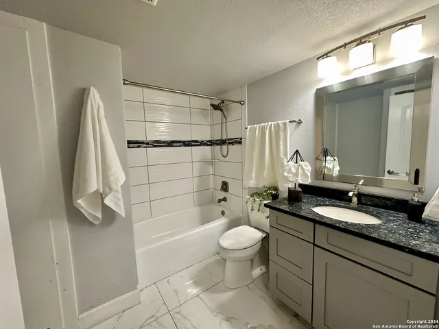 a bathroom with a granite countertop sink toilet and shower